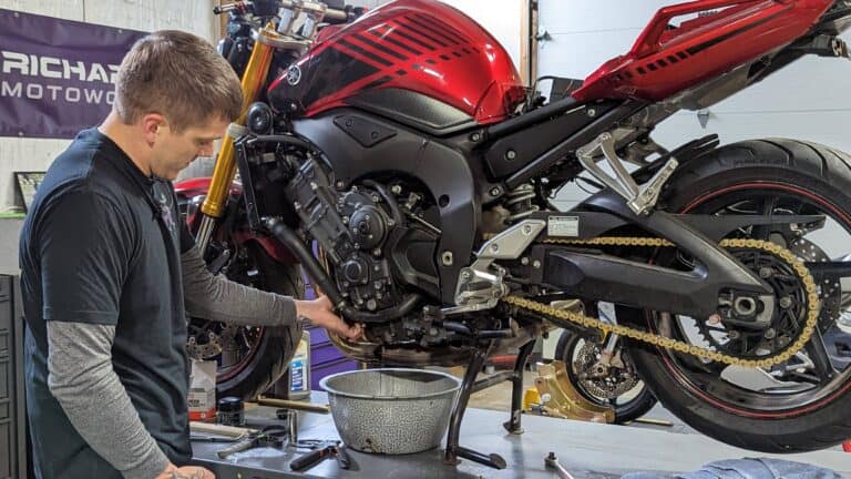 Photo of Ryne, owner of Richardson Motoworks, changing oil on a motorcycle
